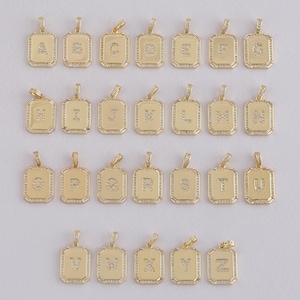 May include: A collection of gold-colored rectangular pendants, each featuring a different letter of the alphabet. The letters are encrusted with small, clear gemstones, and the pendants have a decorative border. The pendants are designed for jewelry.