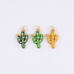 Puede incluir: Tres colgantes de cactus en verde, amarillo y naranja con detalles dorados. Cada colgante presenta una flor roja y pequeños puntos blancos. Los colgantes están diseñados con un lazo en la parte superior para una fácil fijación.