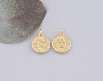 May include: Two gold-toned sun charm pendants with a face and rays. The charms are round and have a detailed design.