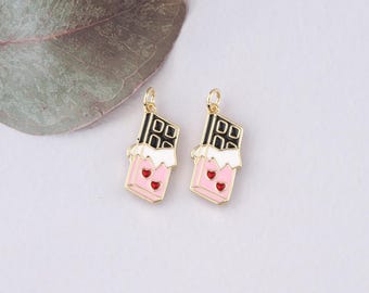 Può includere: Due ciondoli dorati a forma di barrette di cioccolato con glassa rosa e bianca e cuori rossi.