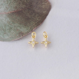 Puede incluir: Dos abalorios de estrella de tono dorado con un solo strass transparente en el centro de cada estrella.