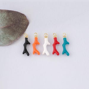 May include: Five coral branch charms in different colors: black, orange, white, red, and turquoise. Each charm has a gold loop for attaching to jewelry.