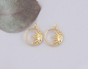 May include: Two gold-toned metal sun charm pendants with a circular design. The sun has a face and rays emanating from it.