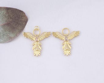 May include: Two gold-colored angel pendants with outstretched wings and a halo. Each pendant features a central teardrop-shaped stone and is embellished with small, sparkling crystals. The wings and lower body have detailed feather-like designs.