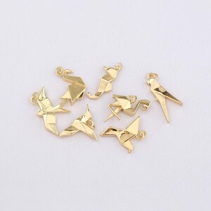 K&ouml;nnte beinhalten: Eine Sammlung goldfarbener Origami-Vogelanh&auml;nger, darunter ein Papagei, ein Kranich und andere Vogelformen. Jeder Anh&auml;nger hat eine kleine Schlaufe zum Befestigen an Schmuck oder anderen Bastelarbeiten. Die Anh&auml;nger werden auf einer wei&szlig;en Oberfl&auml;che pr&auml;sentiert.