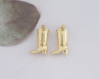 May include: Two gold-colored boot charms with intricate designs. The charms are shaped like cowboy boots and have a detailed pattern on the shaft.