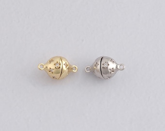 May include: Two spherical jewelry clasps. One is gold-toned with star-shaped cutouts and small clear stones. The other is silver-toned with similar star-shaped cutouts. Both have small loops on each end for attachment.