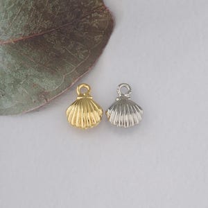 May include: Two small seashell charms, one gold and one silver, with a loop at the top for attaching to jewellery.