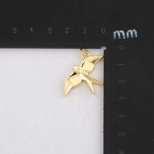 K&ouml;nnte beinhalten: Ein goldfarbener Anh&auml;nger in Form eines Vogels, m&ouml;glicherweise einer Schwalbe, mit einem geometrischen, origami-&auml;hnlichen Design. Der Anh&auml;nger hat oben eine kleine Schlaufe f&uuml;r eine Kette. Der Anh&auml;nger ist etwa 3,8 cm lang.