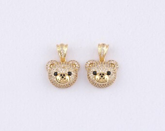 Puede incluir: Dos colgantes dorados con forma de oso. Cada colgante presenta un diseño de cabeza de oso incrustado con pequeños cristales transparentes. Los ojos del oso son negros, y la nariz y la boca también están detalladas. Los colgantes tienen un lazo en la parte superior para una cadena.