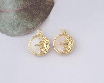 May include: Two gold-toned sun charm pendants with a white mother of pearl center. The sun design is detailed and intricate.