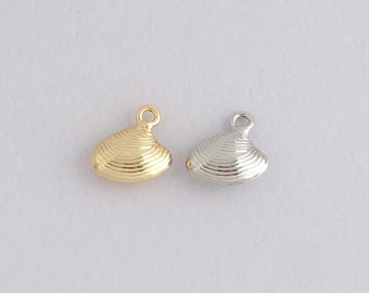 May include: Two small seashell charms, one gold and one silver, are shown against a plain backdrop. Each charm has a loop at the top for threading and detailed ridged texture, suitable for jewellery making or craft projects.