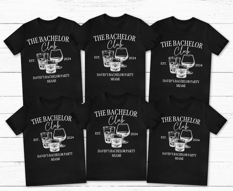 May include: Six black short-sleeve t-shirts featuring a white graphic of three glasses and the text THE BACHELOR Club EST. 2024 DAVID'S BACHELOR PARTY MIAMI. The design includes a tall glass, a short tumbler, and a rounded brandy snifter glass.