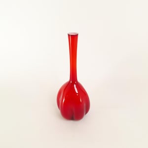 May include: A vibrant red glass vase with a bulbous base and a slender, elongated neck. The vase has a glossy finish and a smooth, rounded form. The overall shape resembles a garlic clove. This decorative vase is suitable for floral arrangements.