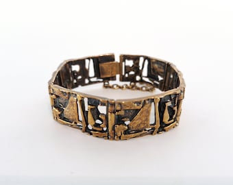 May include: A gold-toned bracelet with a geometric design. The bracelet is made of metal and has a clasp closure.