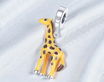 May include: A yellow and brown giraffe charm with a silver clasp. The giraffe has brown spots and silver feet. The charm is designed to be attached to a bracelet or necklace.