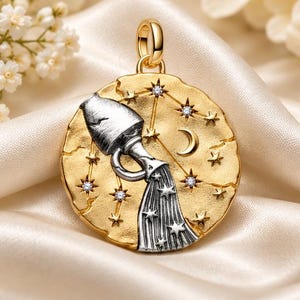 May include: A round gold pendant featuring a silver Aquarius water bearer figure pouring water. The textured gold surface is decorated with a crescent moon and multiple small stars, some of which are accented with tiny clear inset stones.
