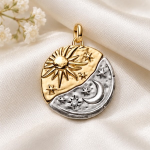 Può includere: Un ciondolo circolare dal design diviso, con un sole e stelle color oro su una metà e una luna crescente e stelle color argento sull'altra. La sezione argentata include una piccola gemma rotonda e trasparente incastonata in una stella.