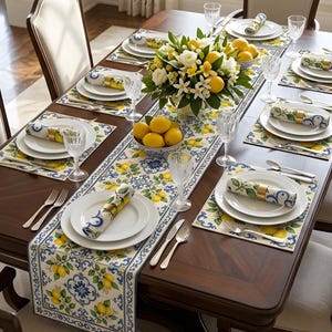 Pode incluir: Uma mesa de jantar retangular de madeira posta para seis pessoas com um caminho de mesa e jogos americanos com padrões azuis e brancos e ilustrações de limões amarelos. Cada lugar inclui um prato branco, guardanapo e talheres.