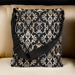 Może przedstawiać: Czarna torba na ramię z wzorem w kolorze złotym i srebrnym. Torba ma regulowany czarny pasek.