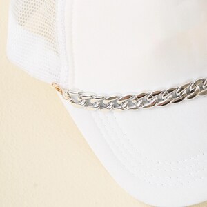 May include: White mesh trucker hat with a silver chain detail around the brim.