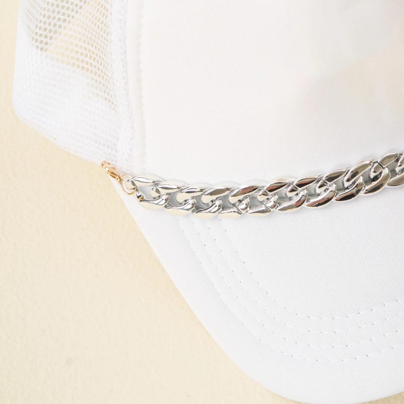 May include: White mesh trucker hat with a silver chain detail around the brim.