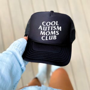 May include: Black trucker hat with white text that reads "COOL AUTISM MOMS CLUB".