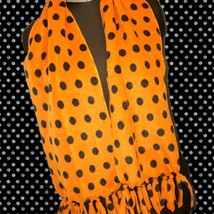 May include: Orange fleece scarf with black polka dots and black fringe.