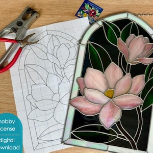 May include: Stained glass window art featuring pink and yellow flowers with green leaves. The window is arched and has a black background. A printed pattern and tools are next to the window. The text "hobby license digital download" is visible.