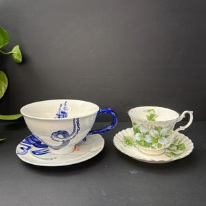 May include: A set of three ceramic mugs with a speckled, matte finish. The mugs are in shades of cream, light gray, and dark gray. Each mug has a simple, minimalist design, perfect for coffee or tea.