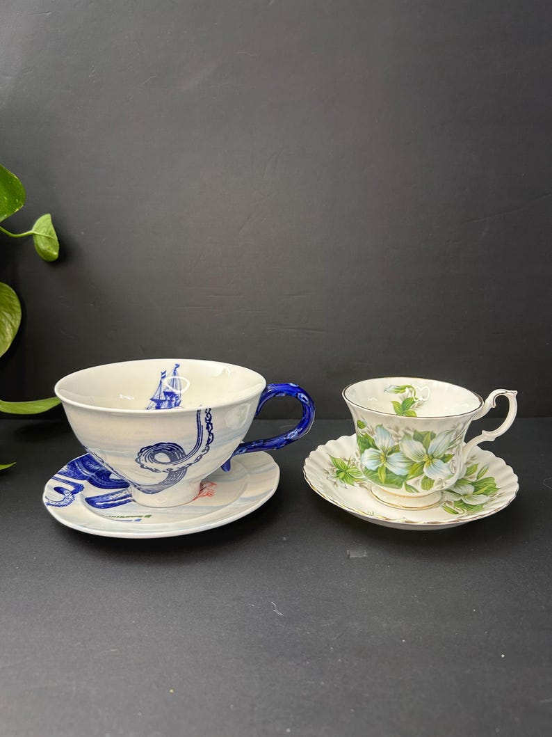 May include: A set of three ceramic mugs with a speckled, matte finish. The mugs are in shades of cream, light gray, and dark gray. Each mug has a simple, minimalist design, perfect for coffee or tea.