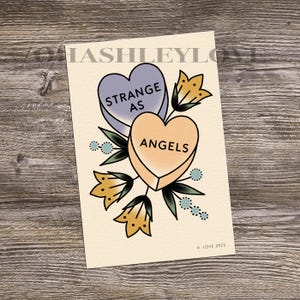 May include: A vintage-style illustration of two candy hearts with the text "Strange as Angels" on a cream background. The hearts are surrounded by yellow and blue flowers.