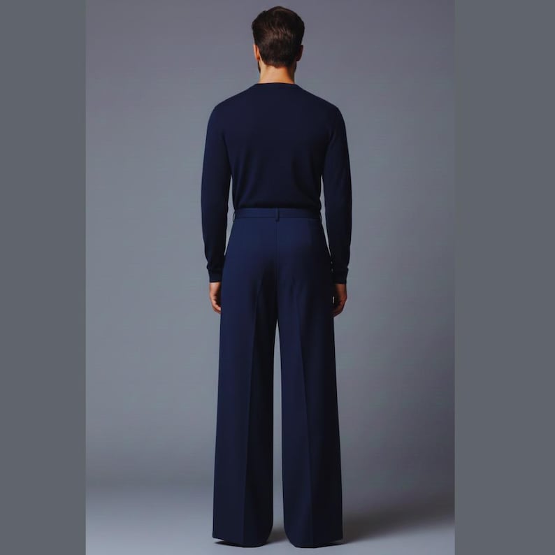May include: A person wearing a navy blue long-sleeved sweater and matching wide-leg trousers. The outfit is a solid color, with a minimalist design. The model is standing against a gray background.