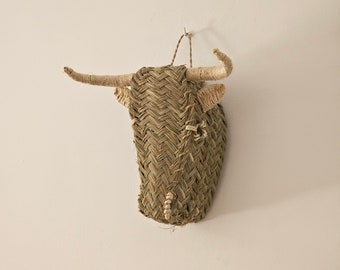 May include: A woven bull's head wall decor made of natural materials, with a light brown color and a simple design.