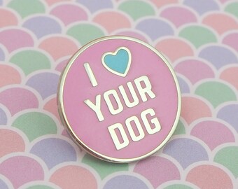 May include: Pink enamel pin with a silver border. The pin features a blue heart and the text "I love your dog".