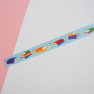 Light blue washi tape printed with small stacks of colourful books and gold-foil sparkles.