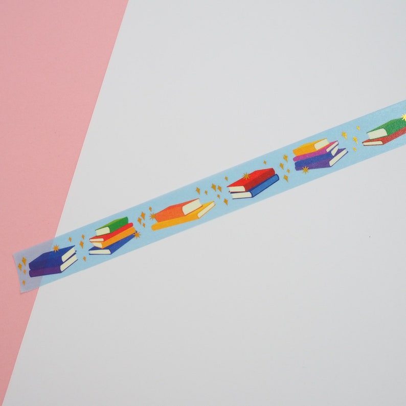 Light blue washi tape printed with small stacks of colourful books and gold-foil sparkles.