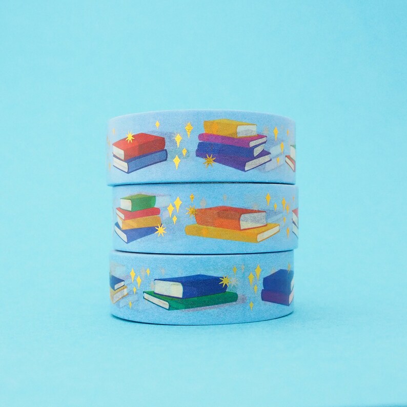 Light blue washi tape printed with small stacks of colourful books and gold-foil sparkles.