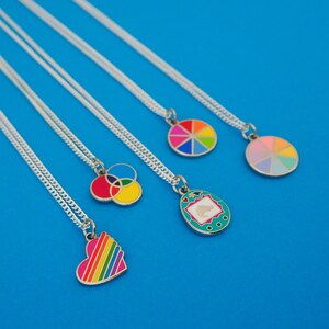 Five silver curb-chain necklaces, each with an enamel charm pendant. The pendants are of different colourful designs.