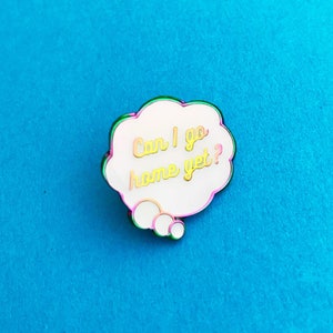 May include: A white enamel pin shaped like a thought bubble with a rainbow outline. The text inside the bubble reads "Can I go home yet?"