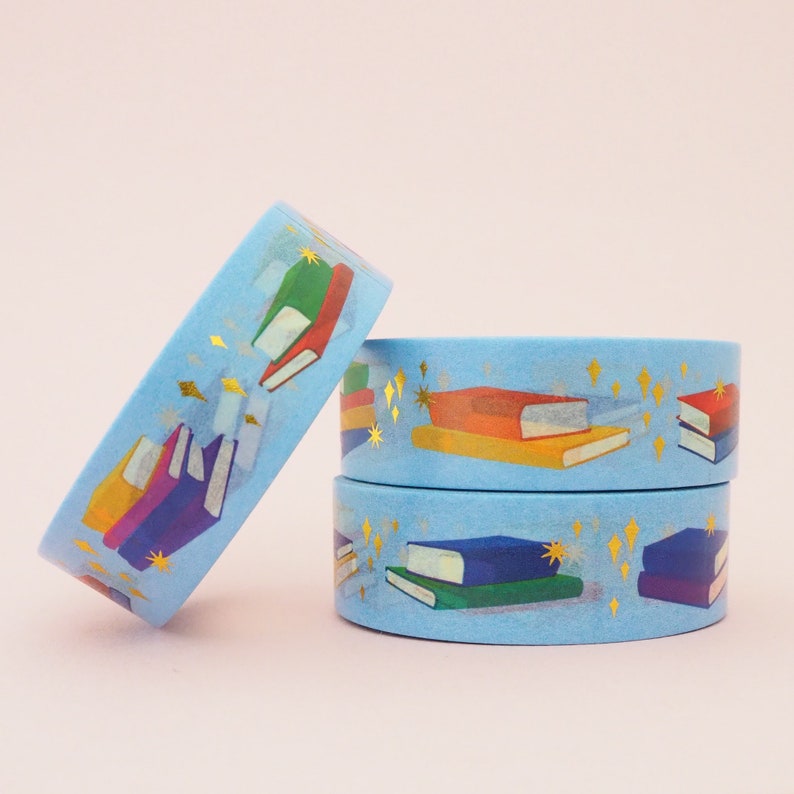 Light blue washi tape printed with small stacks of colourful books and gold-foil sparkles.