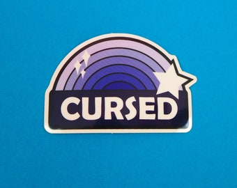 May include: A purple and white sticker with a rainbow design and the word "CURSED" in white letters. The sticker has a white star on the right side.