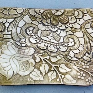 May include: A ceramic dish with a raised design of a floral pattern in white on a green background.