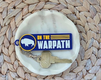 Llavero o etiqueta para bolso de Buffalo Hockey "On the Warpath" en azul y amarillo.