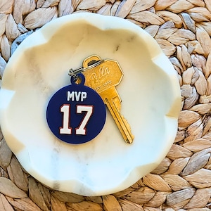 May include: A blue and white round keychain with the text "MVP 17" on it. The keychain is attached to a gold key.