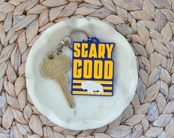Llavero o etiqueta para bolso de Buffalo Hockey "Scary Good" en azul y amarillo.