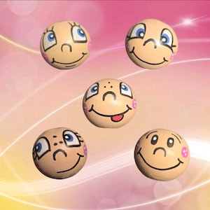Könnte beinhalten: Fünf runde Holzperlen, jede mit einem einzigartigen Cartoon-Gesicht bemalt, das blaue Augen, schwarze Umrisse und rosa Wangenflecken aufweist. Die Ausdrücke variieren, darunter Lächeln, Zwinkern und eine herausgestreckte Zunge auf beigem Grund.