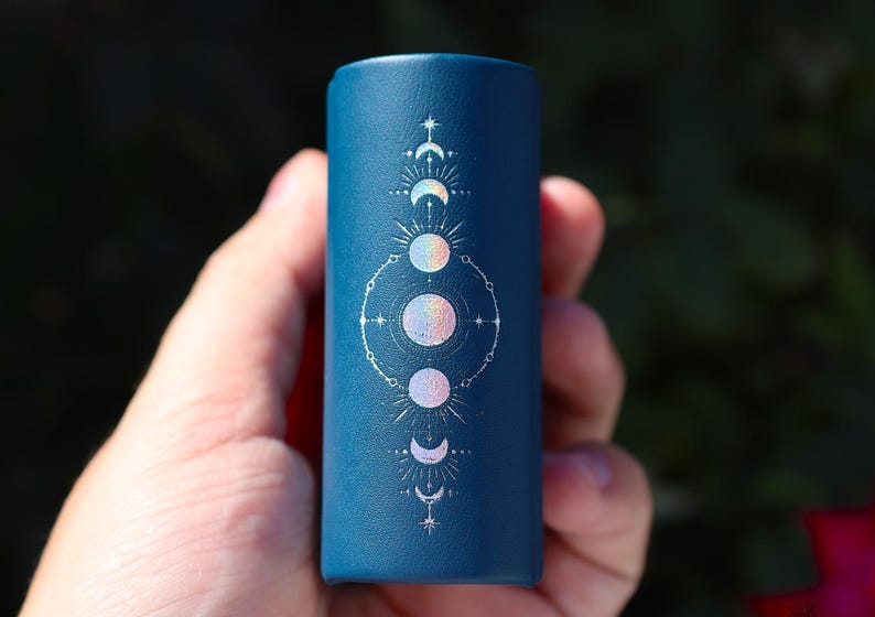 Peut inclure: Un r&eacute;cipient cylindrique bleu fonc&eacute; avec un motif de lune et d'&eacute;toile blanc. Le motif pr&eacute;sente cinq lunes dans diff&eacute;rentes phases, entour&eacute;es d'&eacute;toiles et d'un cercle.