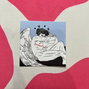 May include: A black and white illustration of an angel with wings, embracing themself. The angel has a red line across their chest and is surrounded by small pink hearts on a light blue background.