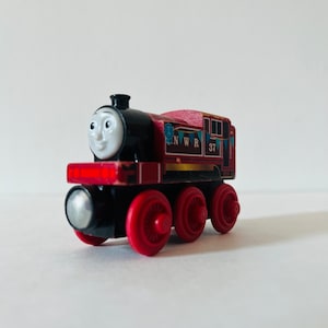 May include: A red and black wooden toy train engine with a friendly face, the words "N.W.R. 37" and blue and white bunting printed on the side.